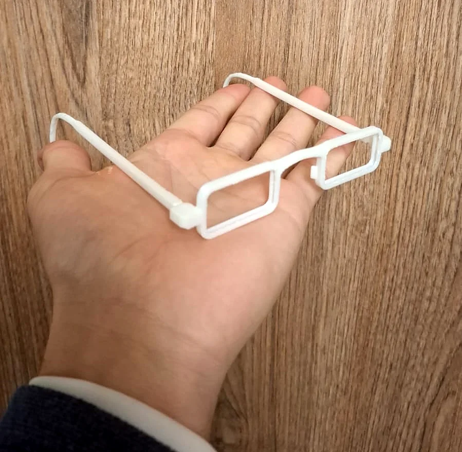 Montura de anteojos blanca impresa en 3D en PETG apoyada sobre una mano
